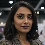 A headshot of Zara Khan, a woman with dark hair and smoky eye makeup, smiling slightly for the camera in an indoor setting.