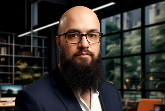 Professional 3D artist Ibtisaam Siddiq in a dark suit with a thick beard, an office in the background with natural light and a modern, minimalist design.
